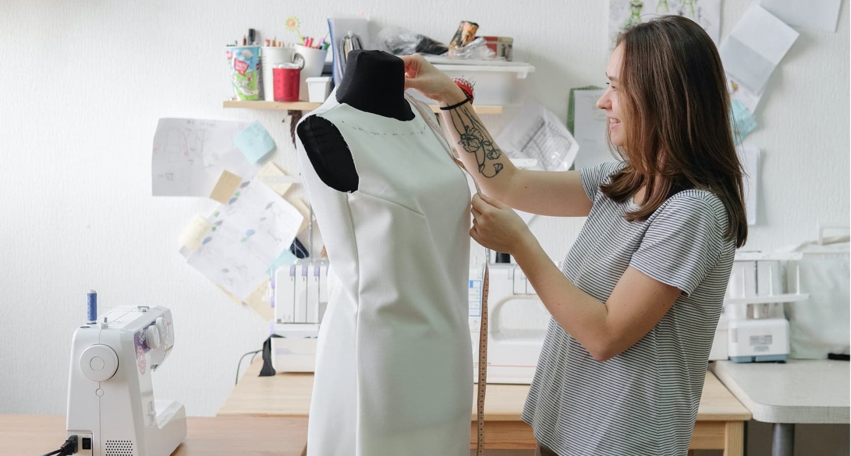 Mujer tomando medidas sobre un vestido blanco en un maniquí, dentro de un taller de costura